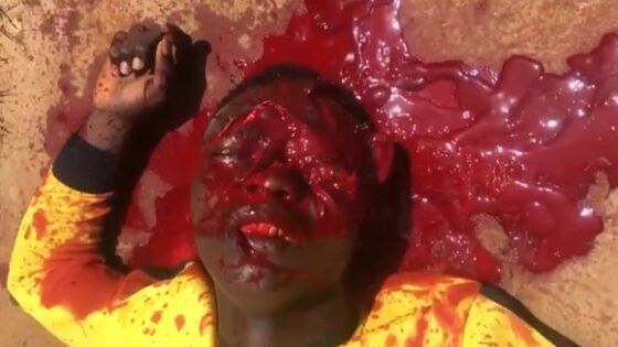 Man with a yellow t shirt contrasting with red blood and a blown off head agonizing in pain in nigeria gang war Photo 0001 Video Thumb